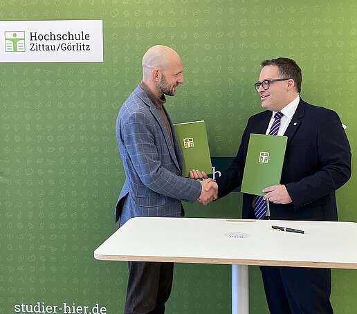 Landrat Dr. Stephan Meyer und Rektor Prof. Dr.-Ing. Alexander Kratzsch geben sich nach der Unterzeichnung des Kooperationsvertrags die Hand.