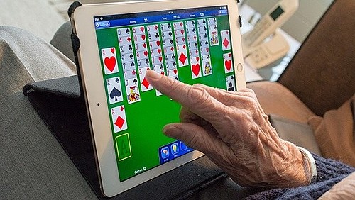 Ältere Mensch spielt Karten auf ipad