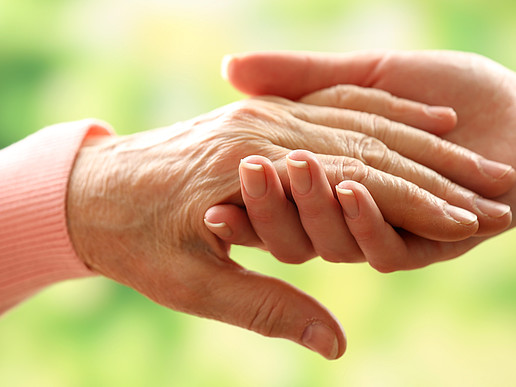 Zwei Hände, die einer alten und einer jungen Frau gehören, halten sich.