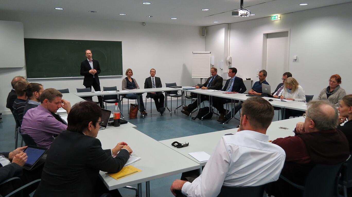 13 Gründungsmitglieder sitzen im Rund und hören Prof. Hoff zu