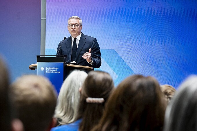 Bundesdigitalminister Dr. Karsten Wildberger spricht an einem Rednerpult vor Publikum.