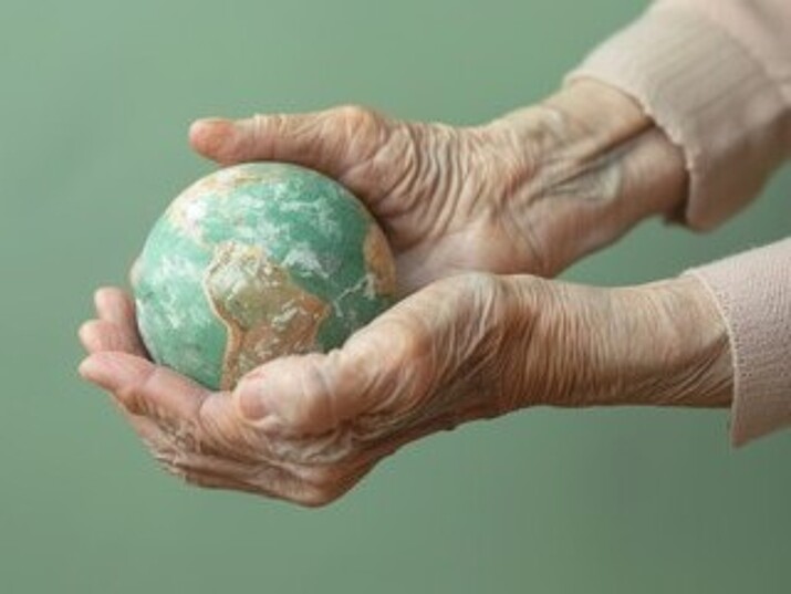 Die Hände einer älteren Dame halten eine kleine Weltkugel