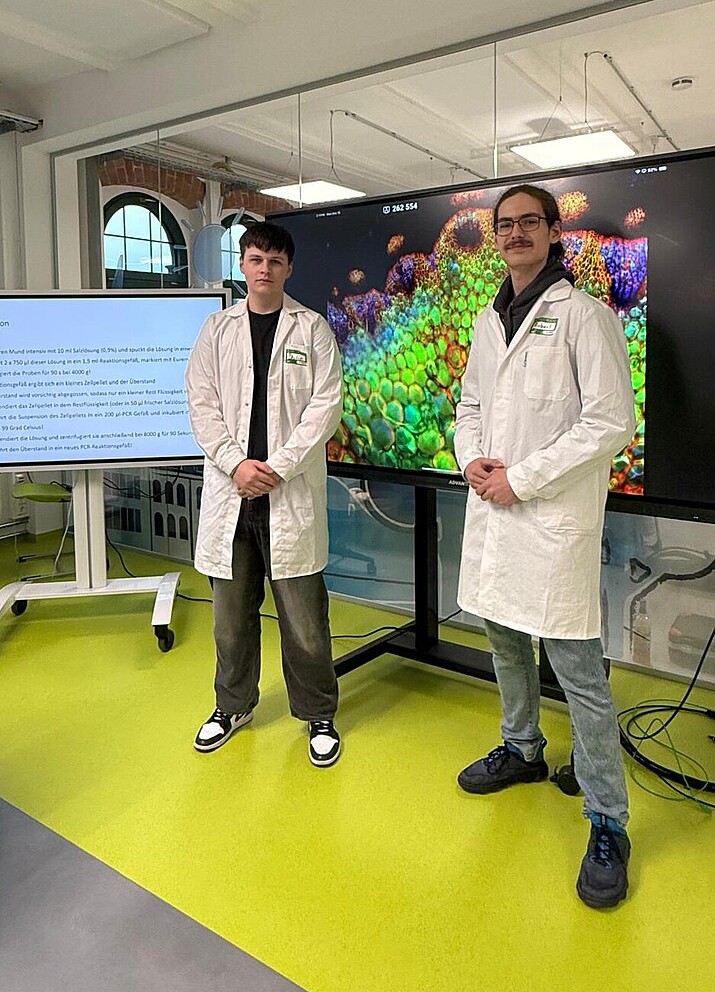 Zwei Bufdis stehen im weißen Laborkittel im School Lab.