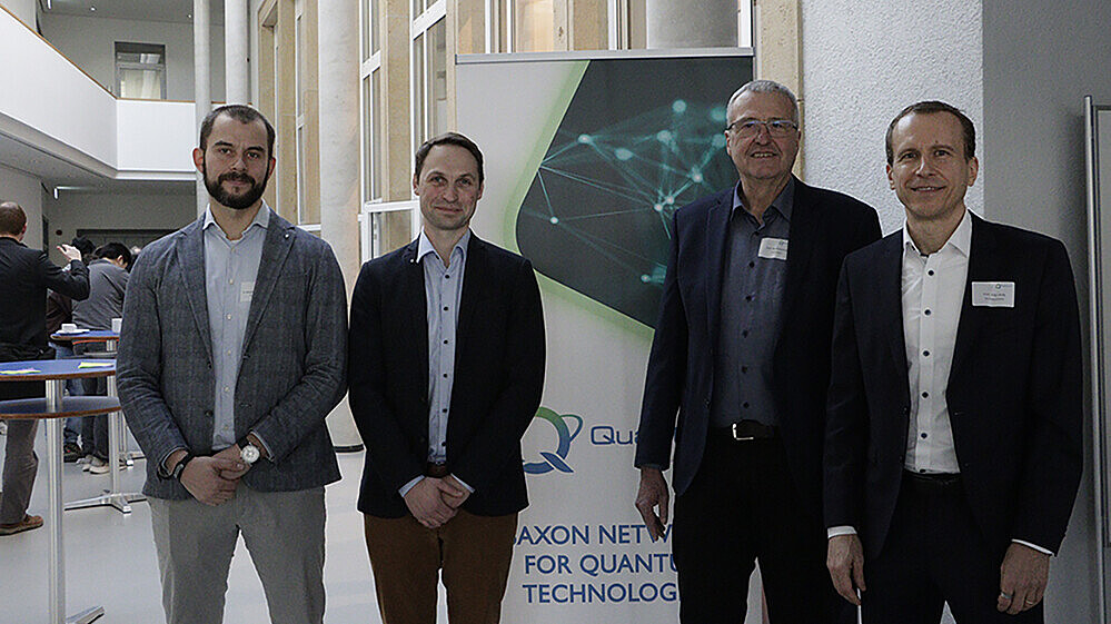 Vier Männer stehen vor einem Roll-up.