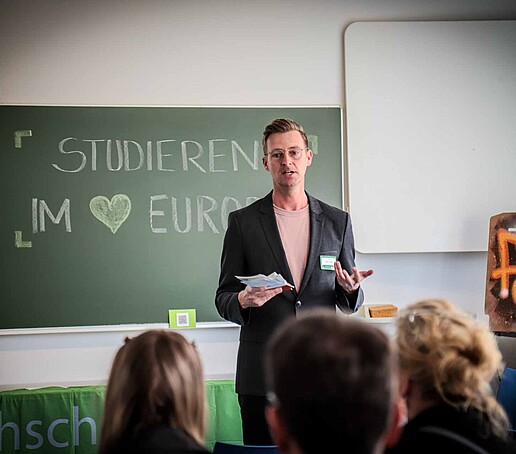 Herr Donath steht vor einer Gruppe vor ihm sitzenden Studieninteressierten und informiert zum Orientierungsstudium Management.