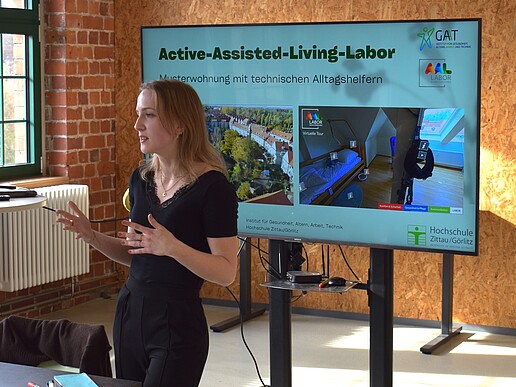 Frau referiert vor einem Monitor
