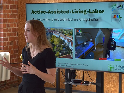 Frau referiert vor einem Monitor