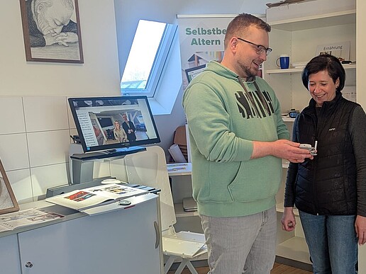 2 Personen stehen im Labor. Ein Mann zeigt einer Frau eine Technologie aus dem Labor.