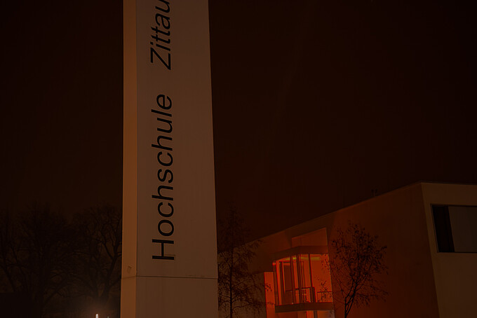 Nach Sonnenuntergang erstrahlt aus den Fenstern des Gebäudes Z vier orangenes Licht.