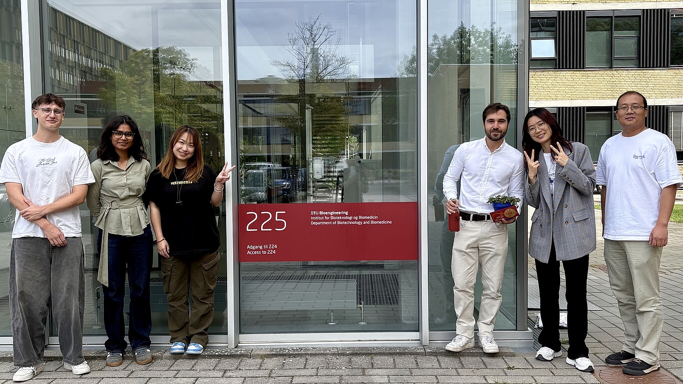 Fabian Gerlach steht gemeinsam mit Mitgliedern seiner internationalen Forschungsgruppe vor dem Gebäude des Department of Biotechnology and Biomedicine der Technical University of Denmark.