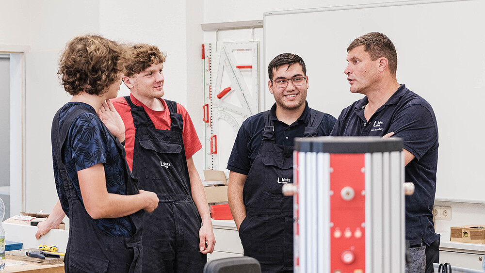 Vier KIA-Studenten und ihr Ausbilder stehen zusammen und unterhalten sich.