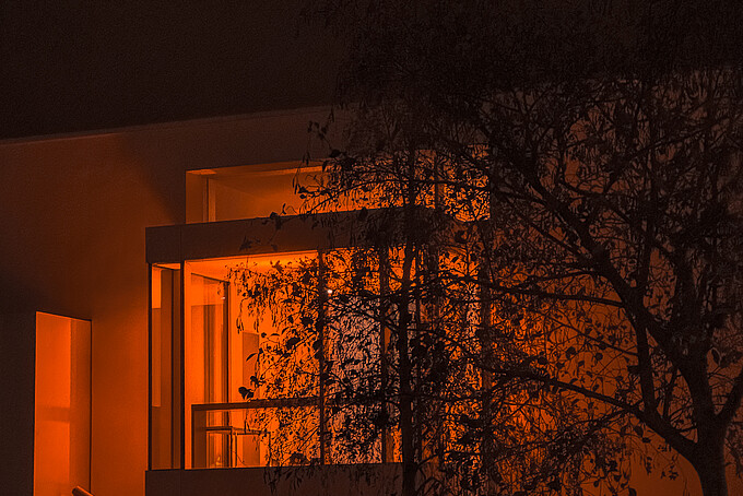 Nach Sonnenuntergang erstrahlt aus den Fenstern des Gebäudes Z vier orangenes Licht.